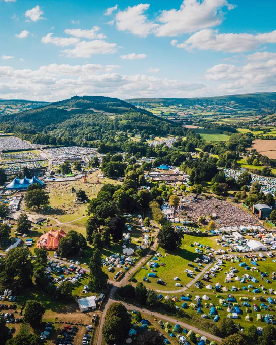 Aerial view of Green Man 2024 with tents, crowds, and green rolling hills.
