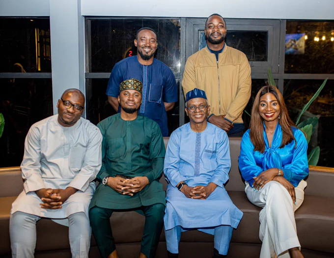 A group of 5 men and 1 woman smiling.