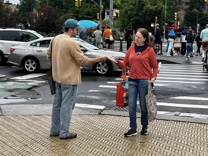 NYT Tech Member John Cruickshank handing a flyer to a pedestrian