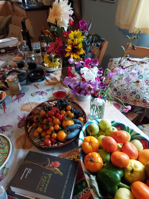 Table crammed with autumn flowers, fruit and a book of Tagore's writings 