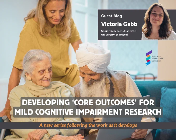 The image features a guest blog announcement for Victoria Gabb, a Senior Research Associate at the University of Bristol. The title of the blog is "Developing 'Core Outcomes' for Mild Cognitive Impairment Research," and it is part of a new series following the development of this work. The image shows a smiling elderly couple, one of whom is wearing a turban, sitting together and looking at a device, with a younger woman standing behind them, also smiling. This reflects a warm and supportive setting. The Dementia Researcher logo is displayed on the right. The text below the title reads: "A new series following the work as it develops."