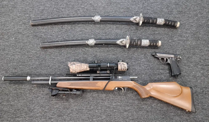 Image of 2 curved swords, 1 modified gas powered rifle and an imitation firearm.