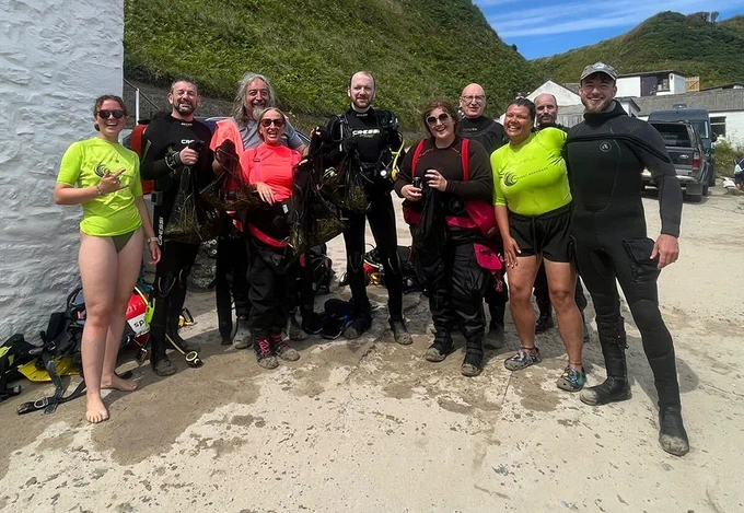 Group of scuba divers, smiling and posing after collecting seagrass seeds in North Wales
