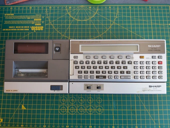 Photo of a Sharp PC-1500 connected to its CE-150 plotter and cassette interface.
