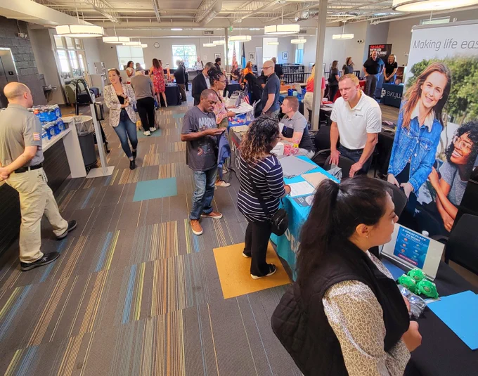 Attendees interact at a bustling corporate event inside a modern office space, featuring promotional materials with the Sysco logo.