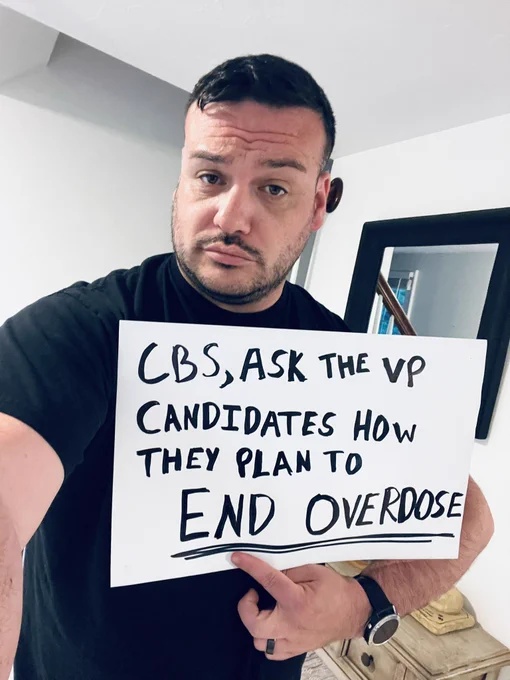 Photo of me holding a sign that says “cbs, ask the VP candidates how they plan to end overdose” - the sign was created by my teenaged  daughter