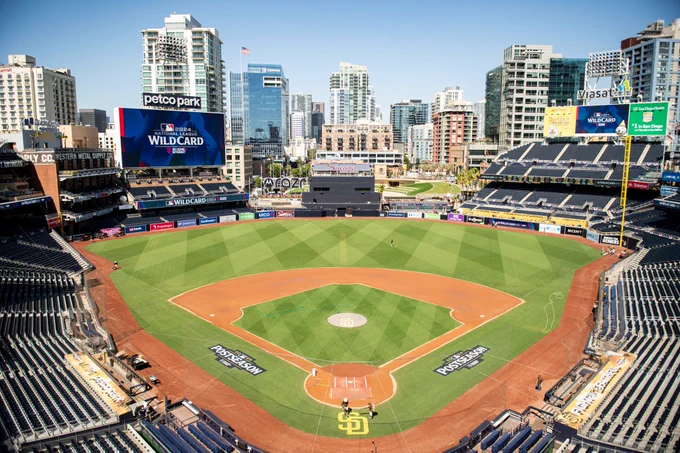 Wide shot of Petco Park taken this morning during Postseason field prep. The boards are showing a graphic that says "2024 National League Wild Card presented by T-Mobile 5G Home Internet". The same logo is painted along the first base and third base line. The top of the visitors dugout reads "Welcome to Petco Park" and the top of the Padres dugout reads "Fight for the Faithful".