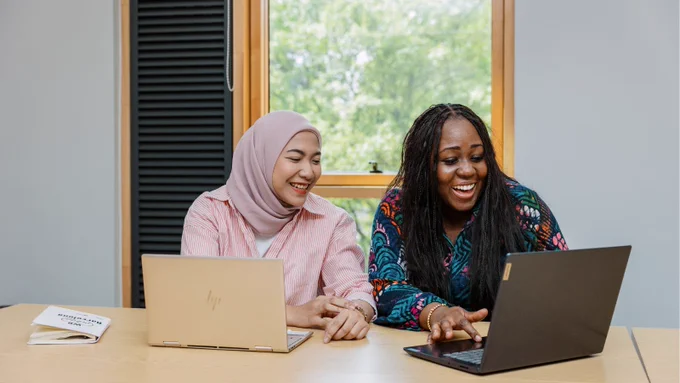 Two postgraduate students working on laptops at the Institute for Transport Studies.