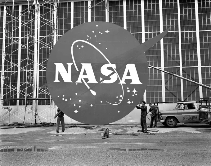 Workers install the NASA “meatball” logo on the front of the Flight Research Building, or hangar, at Lewis Research Center (now NASA Glenn) in 1962.