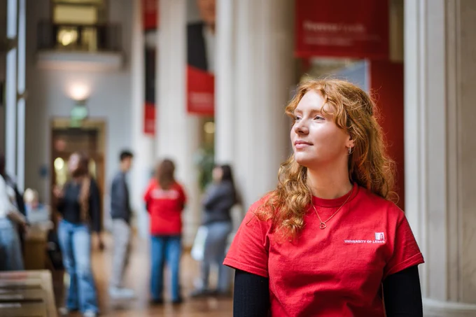 Student poses in red top featuring the University of Leeds logo