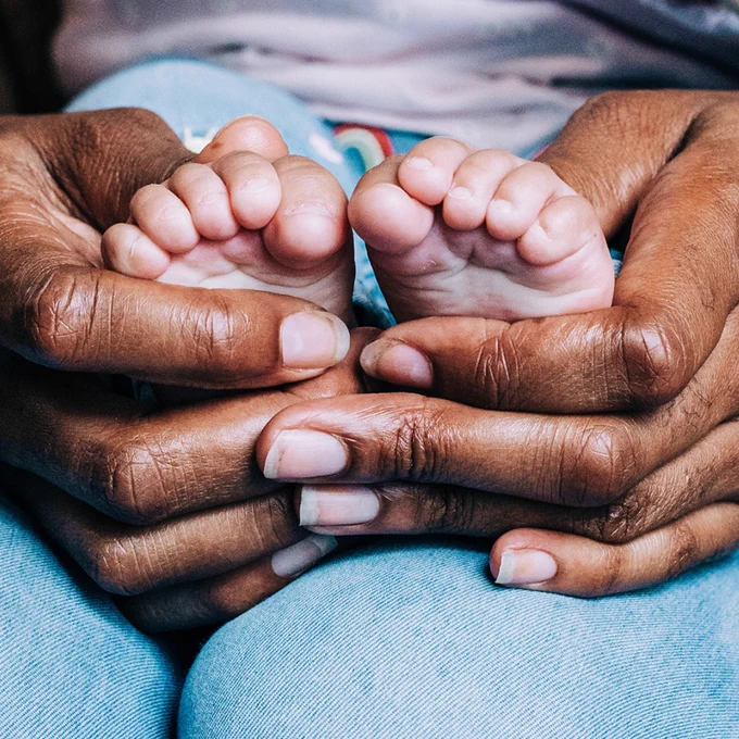 Close up image of hands holding a a babies' feet.