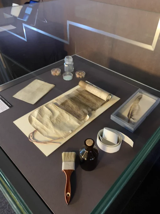 A medieval document in a case surrounded by the tools used in its creation and conservation.