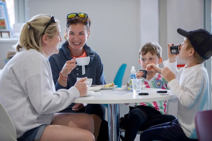 Two ladies and two children are sat happily in our cafe, with drinks and snacks on the table.