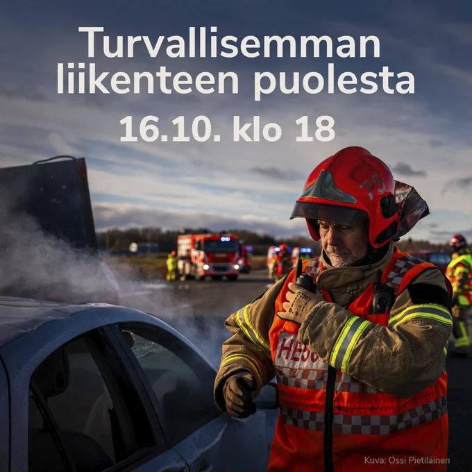 Palomies oranssiruskeassa pelastajan asussa vakava ilme kasvoilla. Vieressä savuava auto. Taustalla pelastustoimen muuta henkilöstöä ja paloautoja.