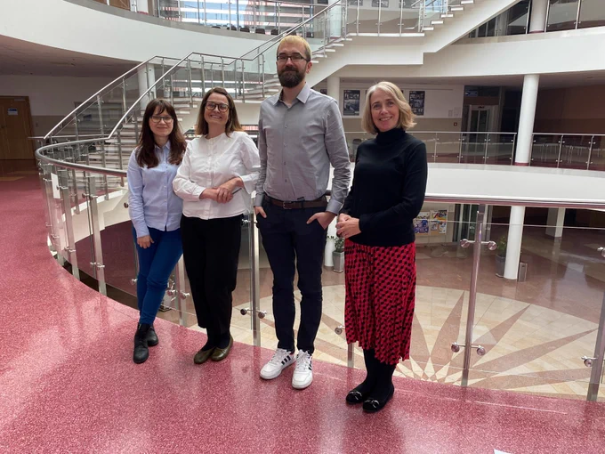 Wielsawa Duzy, Sarah Gearty, Michal Slomski, Rachel Gearty posing for a photograph on an indoor balcony