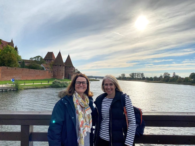 Sarah Geary and Rachel Murphy on a bridge over a river with a castle in the background