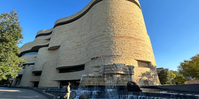 A man observes the exterior of the National Museum of the American Indian. 