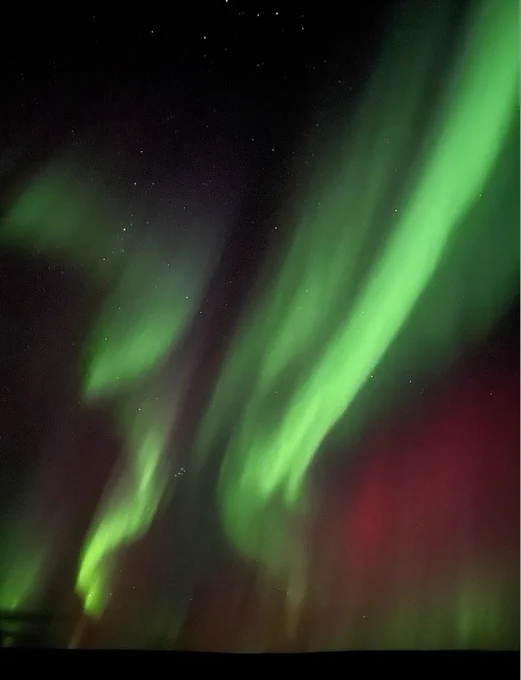 Aurora image taken on 7 October 2024 from the China-Iceland Joint Arctic Observatory near Akureyri (Iceland). We see a sky full of bright green and some red lights, while several stars are visible in the background.