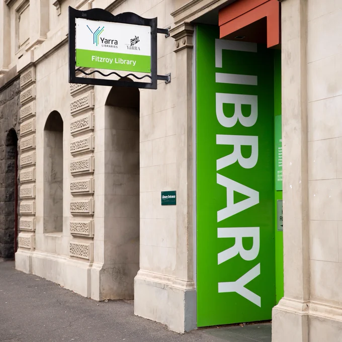Exterior view of Fitzroy Library, featuring a vibrant green and white sign with 'Library' written in bold letters beside the entrance arches.