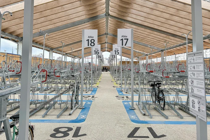 An elegant new 1,200-bike parking facility at Gare du Nord Station in Paris includes integrated signage, a guarded entrance, two-tiered racks, and a repair station.