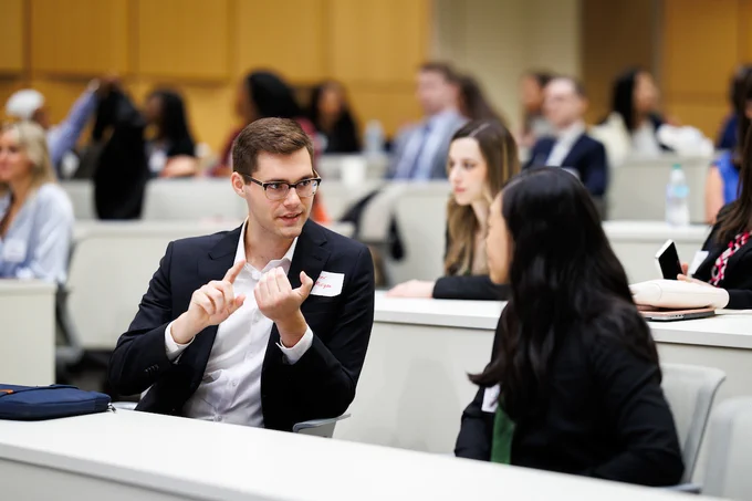 Two students sitting in a classroom, chatting