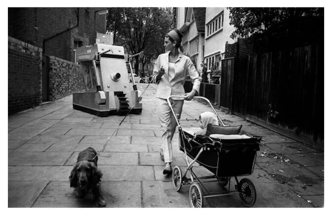 Woman pushing pram away from evil robot. No fucks given