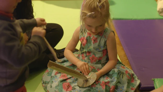 a child sat on a mat crafting. 