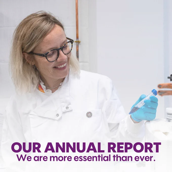 Professor Grazia in a white lab coat smiling while holding a sample in a laboratory, with text overlay stating 'OUR ANNUAL REPORT. We are more essential than ever.'
