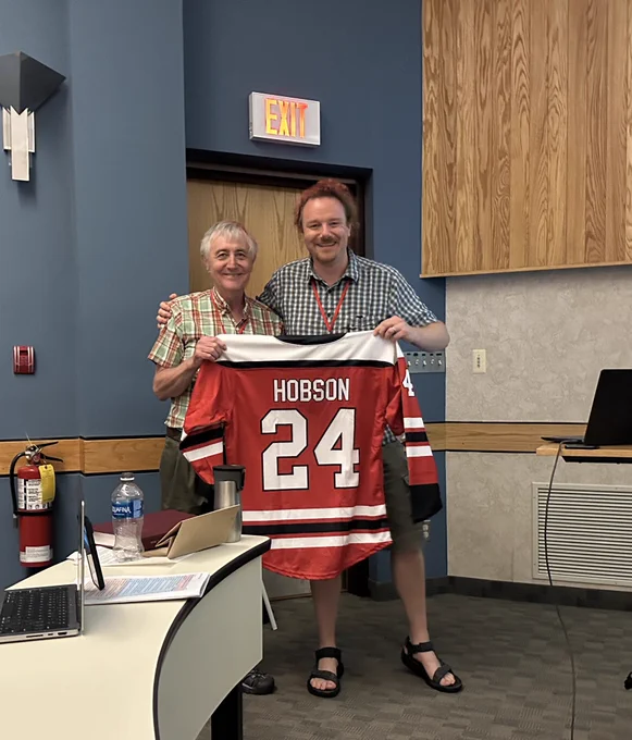 Keith Hobson receives a hockey jersey with the number 24 and his last name, gifted by Brian Hayden, the organizer of IsoEcol2024.