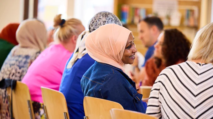 People sat together in a line talking to people opposite, one woman is turned to face another person and is smiling.