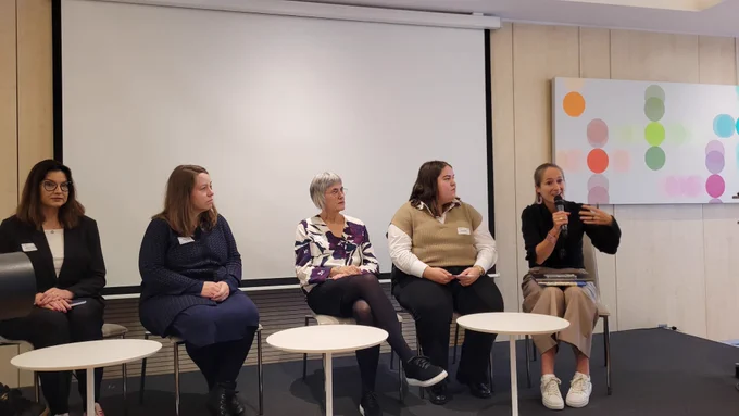 Prof. Beatrix Busse speaking during a panel discussion alongside four other participants.