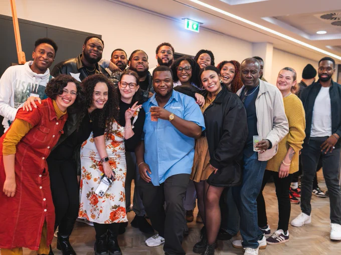 Group of diverse people smiling and posing together at an indoor social gathering.
