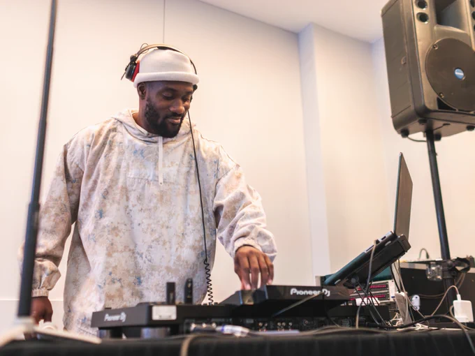 A DJ mixes music on a Pioneer DJ setup at an indoor event.