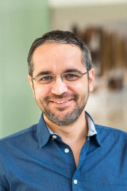 Color head-and-shoulders image of Mircea Dinca against a blurred background.