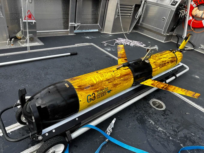 A dirty yellow glider rests on the deck of a boat with 111 days written in the dirt.