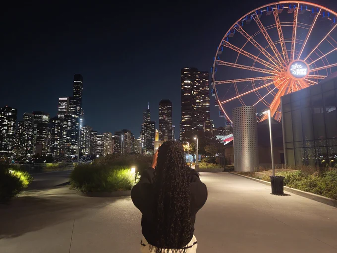 A picture of Clíona at Navy Pier, taking a picture of the Chicago Skyline 