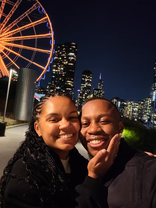 De-Shaine and Clíona Murray smiling at the camera with Navy Pier and the Chicago skyline in the night in the background.