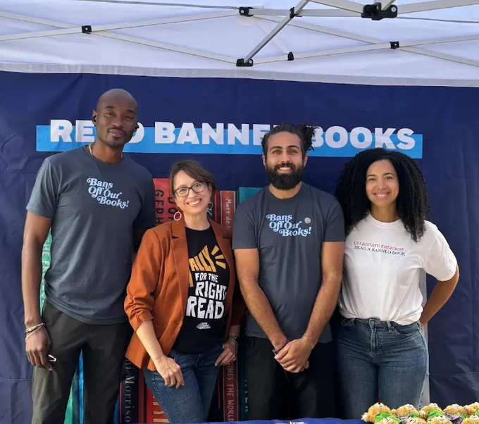 Penguin Random House staff and a Unite Against Book Bans representative stand in front of a Read Banned Books backdrop.