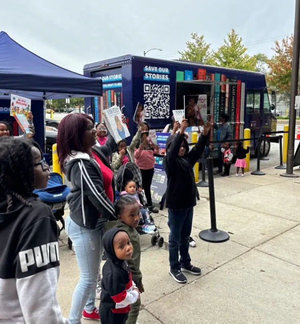 Library patrons hold up books near the Banned Wagon.