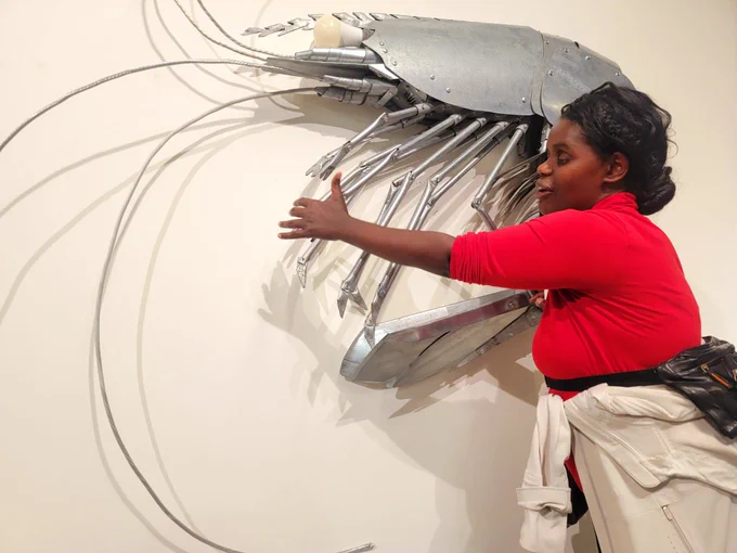 A woman touches a metal sculpture of a shrimp
