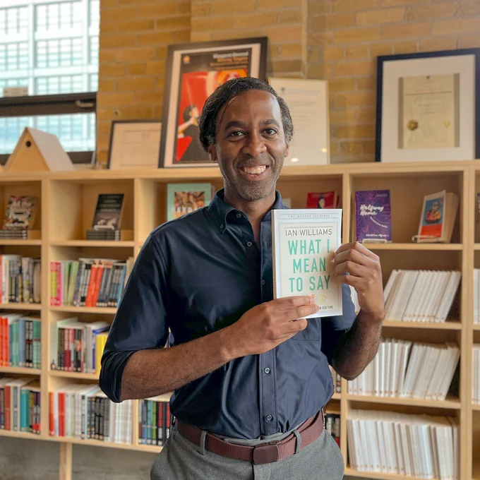 A photo of Ian Williams holding a copy of What I Mean To Say. 