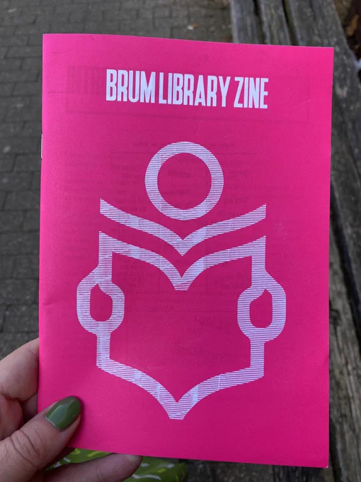 Bright pink pamphlet held in hand. Title reads Birrmingham Library Zine with logo of person reading an open book