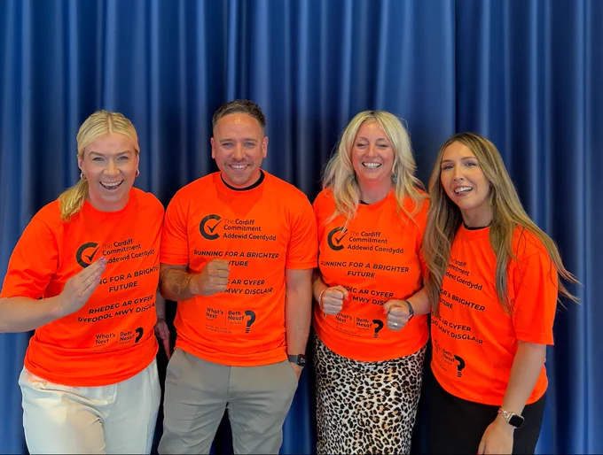 Four people pose in running t-shirts.