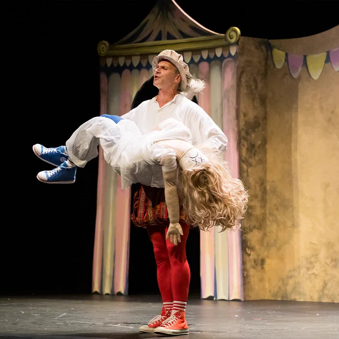 Man in Shakespeare costume hold human size doll like its dead.