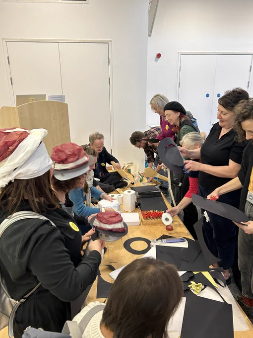 A group of teachers works together as they create art from paper, card and masking tape.