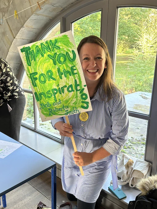 A woman holds up a placard with a painted slogan. It reads: ‘Thank you for the inspiration Bob and Roberta Smith’.