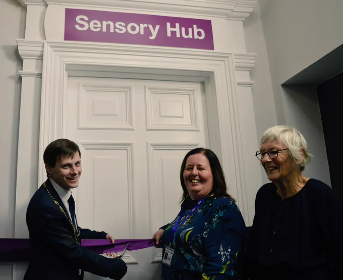 The Provost,  CEO & President of VisionPk, holding a purple ribbon across the Sensory Hub door to officially open the hub