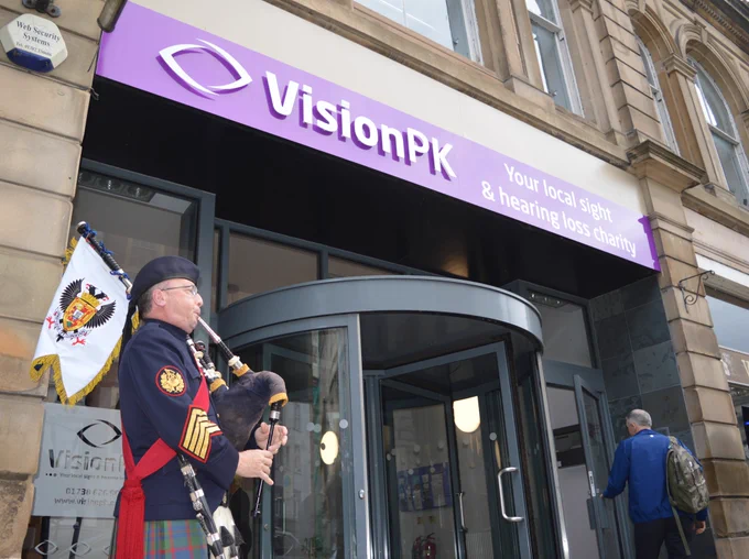 A piper playing outside VisionPK sensory hub welcoming guests