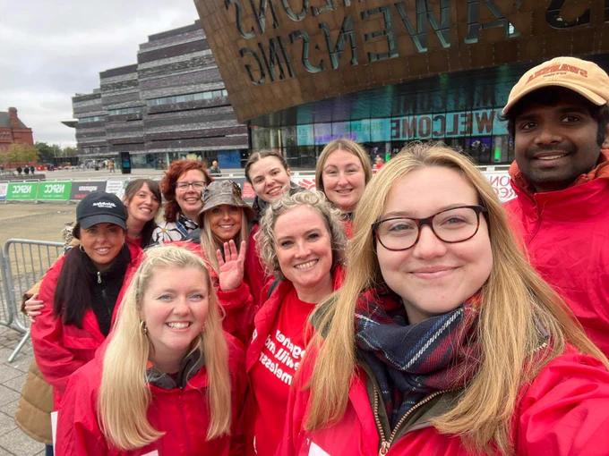 A group of people wearing Crisis branded clothes in front of the Wales Millenium Centre.