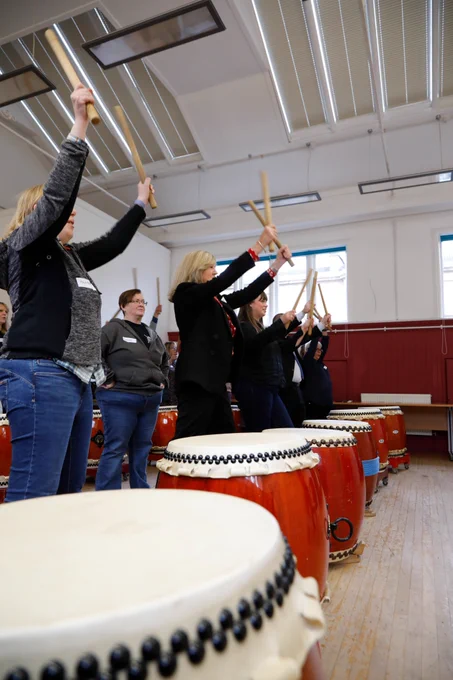 A shot of participants holding drumsticks in the air